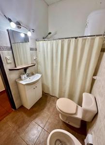 a bathroom with a toilet and a sink and a shower curtain at Apapacho Urbano Casa cómoda Ideal familias y grupos in Paysandú