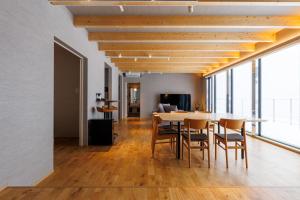 a dining room and living room with a table and chairs at Yunagi 夕凪プライベートサウナ付ヴィラオーシャンフロントの絶景宿 夕日とサウナを満喫海と夕日に包まれる贅沢空間 in Mōrai