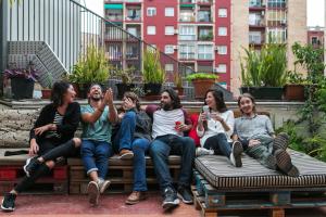 eine Gruppe von Menschen, die auf einer Bank sitzen in der Unterkunft Pars Tailor's Hostel in Barcelona