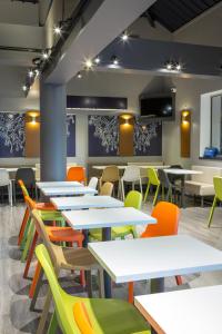 a cafeteria with white tables and colorful chairs at ibis budget Aubagne Paluds Agora in Aubagne