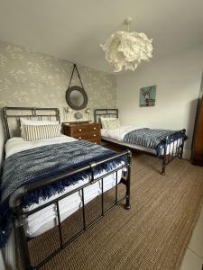 a bedroom with two beds and a chandelier at Highfield Terrace – Cosy Devon Retreat, Close to Beer Beach in Beer