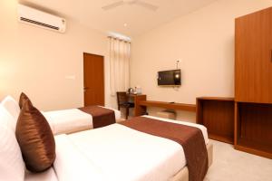 a hotel room with two beds and a desk at HOTEL NARMADA RESIDENCY in Maheshwar