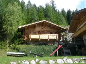 a log cabin with a playground in front of it at Alpenhof Schwaiger - Hotel Garni in Mühlbach am Hochkönig