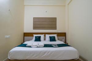 a bedroom with a large white bed with blue pillows at Hotel Aeronest Residency in Calicut