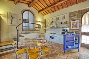 a kitchen with a table and chairs in a room at Poggiluglio by PosarelliVillas in San Gimignano