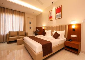 a hotel room with a large bed and a chair at HOTEL NARMADA RESIDENCY in Maheshwar