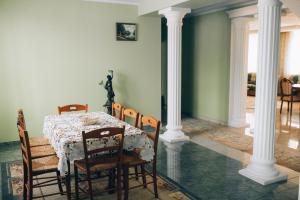 a dining room with a table and chairs and columns at Fermerska Hata in Dubno