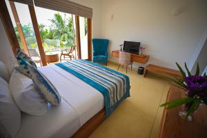 a bedroom with a bed and a desk and a window at Kingfisher Beach in Unawatuna