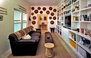 sala de estar con sofá de cuero y estanterías de libros en umSisi House, en White River