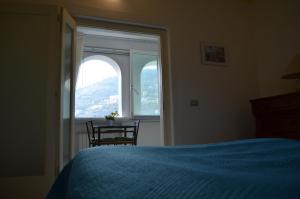 a bedroom with a bed and a table and a window at Casa Cecilia in Ravello