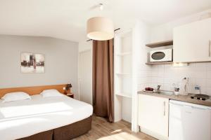 1 dormitorio pequeño con 1 cama y cocina en Séjours & Affaires Tours Léonard De Vinci, en Tours