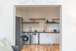a kitchen with white cabinets and a washer and dryer at 2 on Hope in Simonʼs Town