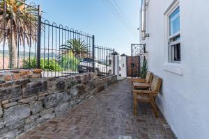 a bench on the side of a building with a fence at 2 on Hope in Simonʼs Town