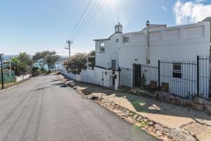 an empty street next to a white house at 2 on Hope in Simonʼs Town