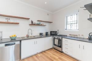 a kitchen with white cabinets and stainless steel appliances at 2 on Hope in Simonʼs Town +1 photo