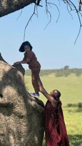 a young girl is climbing on the back of an elephant at Bwana Renman Campsite in Narok