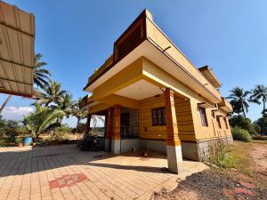 a small yellow house with a porch at Laksh Nivas Fields Stay in Udupi