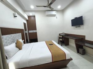 a bedroom with a bed and a desk and a television at Sathya Comforts in Bangalore