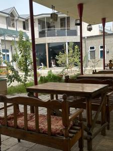 a wooden table and benches sitting under an umbrella at Home Villa YaaxYa in Bukhara
