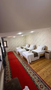 a group of four beds in a room with a red rug at Home Villa YaaxYa in Bukhara