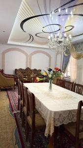 a dining room with a table with a vase of flowers at Home Villa YaaxYa in Bukhara