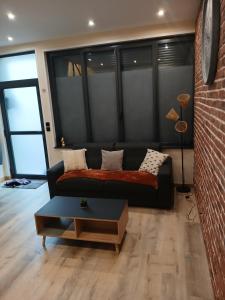 a living room with a couch and a brick wall at Duplex 4 Personnes 5 Minutes a pied du petit port et 10 Minutes de la plage in Le Havre