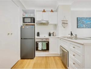 a kitchen with white cabinets and a stainless steel refrigerator at House 4-bed 2-bath Caboolture South in Caboolture