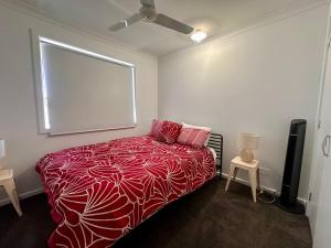 a bedroom with a bed with a red blanket and a window at House 4-bed 2-bath Caboolture South in Caboolture