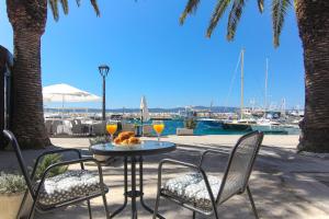 a table with two chairs and two glasses of orange juice at Apartments Nikolina in Podgora