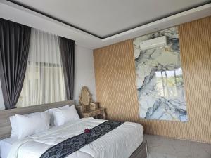 a bedroom with a bed and a large painting on the wall at Arkana Homestay in Tabanan