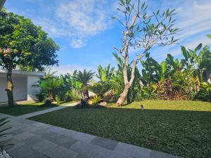 a garden with a lawn with trees and a house at Arkana Homestay in Tabanan +12 photos