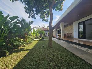 a tree in the middle of a yard next to a building at Arkana Homestay in Tabanan