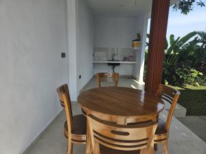 a dining room with a wooden table and chairs at Arkana Homestay in Tabanan