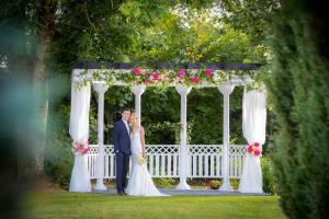 a bride and groom standing in front of a gazebo at Springhill Hotel Kilkenny in Kilkenny