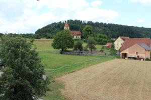 ein Bauernhof mit einem Feld und einer Kirche in der Ferne in der Unterkunft Altes Forsthaus in Gebsattel