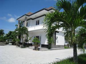 una casa blanca con palmeras delante en Hoa Sua Motel, en Long Hai
