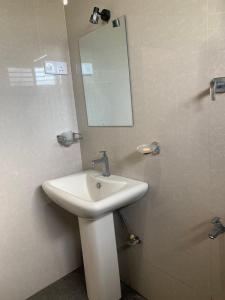 a bathroom with a sink and a mirror on the wall at New Papa Palace in Wattegama