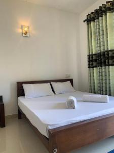a bedroom with a bed with white sheets and curtains at New Papa Palace in Wattegama