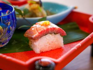 a piece of sushi sitting on a red plate at さめうら荘レイクサイドホテル in Tosa +16 photos