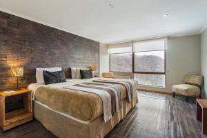 una camera con un grande letto con un muro di mattoni di Hotel Alto Nevados a Nevados de Chillan