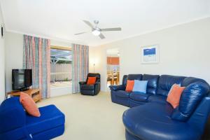 a living room with a blue leather couch and two chairs at 2 Marto Court in Normanville