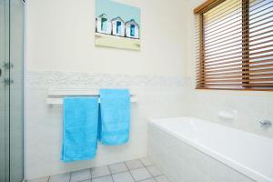 a bathroom with a tub and a shower and blue towels at 2 Marto Court in Normanville +11 photos