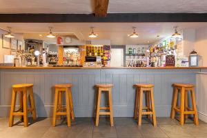un bar con 4 taburetes de madera en un bar en The City Arms, en Wells