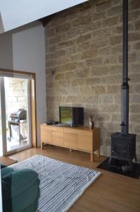 a living room with a tv and a brick wall at Villa de Paco in Sever do Vouga