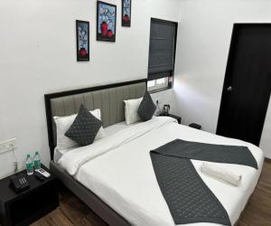 a bedroom with a large bed with white sheets and pillows at Sunny Executive in Satara