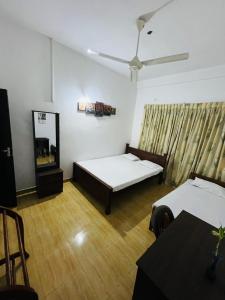 a room with two beds and a television in it at Aluvihare Residence in Matale