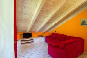 a living room with a red couch and a tv at Chalet La Rugiada in Valdisotto