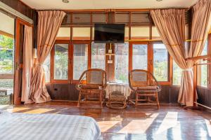 a bedroom with two chairs and a table with a television at De Bua Valley Resort in Wang Nam Khieo