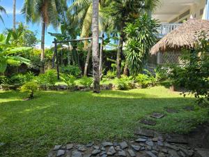 a yard with palm trees and a house at Appartement Baie-Rose SP Nosy-Be in Nosy Be