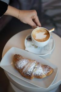 a person holding a cup of coffee and a pastry at Agorà Luxury Experience in Zafferana Etnea